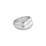 En sølvfarvet ring hviler på en hvid baggrund. Ringen har en tekstureret overflade og en unik, organisk form.