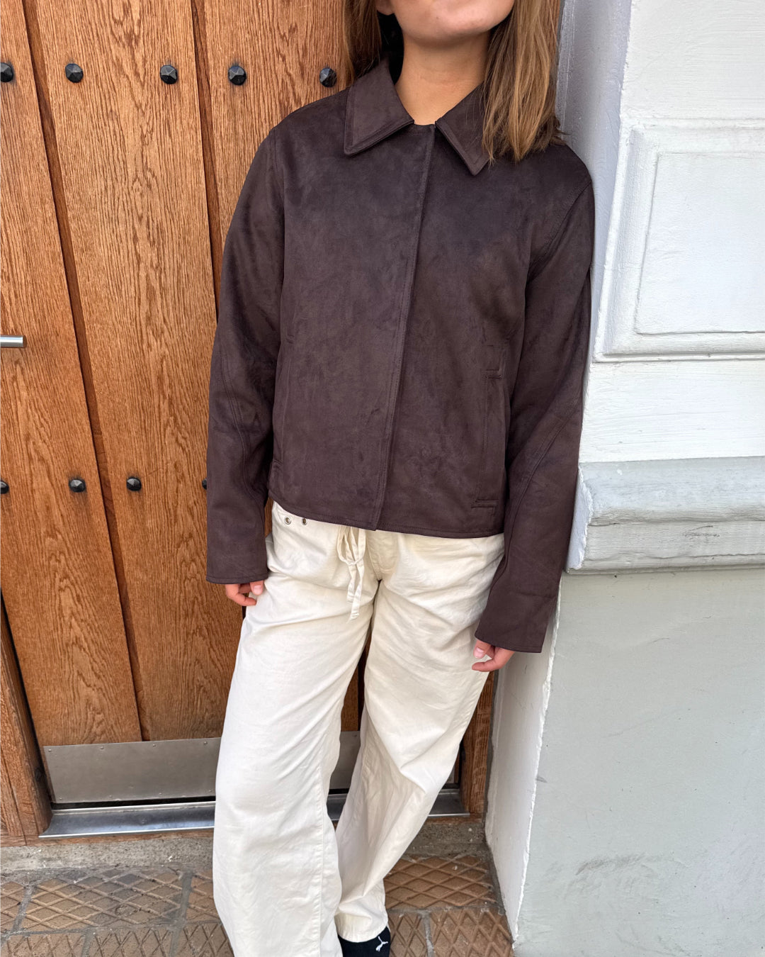 Modelfoto af pige i brun Allie ruskinds jakke og beigefarvede Arianna jeans. Alt er fra BySofieSønderby