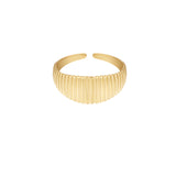 Guldfarvet armring hviler stille mod en ensfarvet baggrund. Den har en rillet overflade for tekstur og et åbent design uden lås.