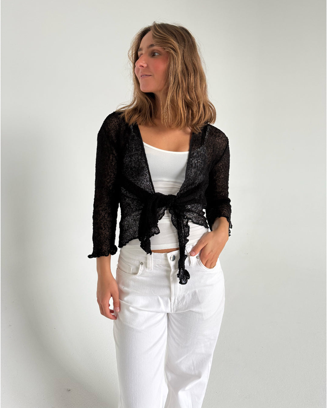 Modelfoto af pige som bærer en Arabella bluse i sort, samt et par hvide jeans. Alt fra By Sofie Sønderby