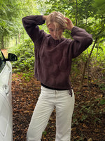 Modelfoto af pige i en brun Bay striktrøje og hvide Nanna jeans. Alt er fra BySofieSønderby