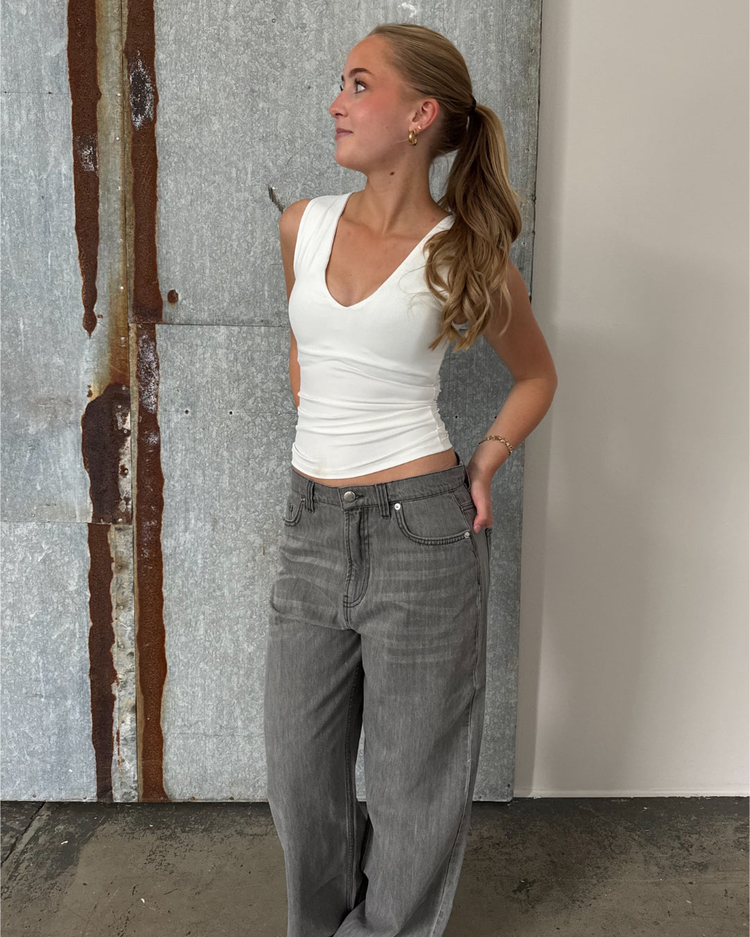 Modelfoto af pige der bærer Blakely top i hvid, samt grå Nanna jeans. Alt fra BySofieSønderby