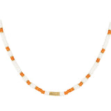 Halskæde af perler, vekslende mellem hvide og orange farver, med en lille guld detalje i midten. Ligger mod en simpel hvid baggrund.