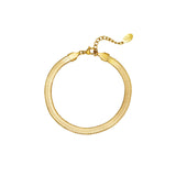 Et guldarmbånd ligger i en cirkulær form med en lille justerbar kæde og vedhæng. Armbåndet hviler på en hvid baggrund og vedhænget har en indgravering.