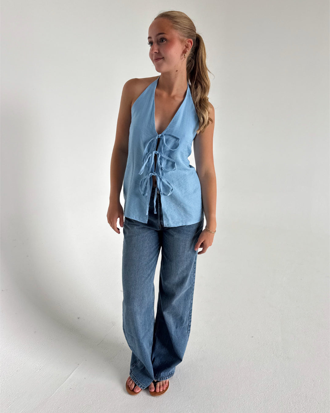 Modelfoto af pige som bærer en Daisy top i blå, samt et par Nanna jeans. Alt fra By Sofie Sønderby