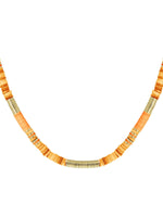 Halskæde med flade orange og gyldne perler arrangeret i mønster; perlerne sidder tæt sammen og danner et buet mønster mod en hvid baggrund.