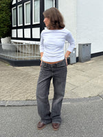 Modelfoto af pige i en hvid Fifi boatneck bluse og grå Nanna jeans. Alt er fra BySofieSønderby