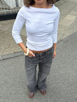 Modelfoto af pige i en hvid Fifi boatneck bluse og grå Nanna jeans. Alt er fra BySofieSønderby