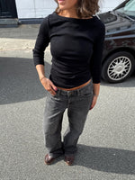 Modelfoto af pige i en sort Fifi boatneck bluse og grå Nanna jeans. Alt er fra BySofieSønderby