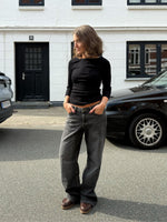 Modelfoto af pige i en sort Fifi boatneck bluse og grå Nanna jeans. Alt er fra BySofieSønderby