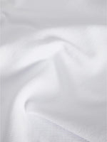 En hvid klud ligger i folder, der skaber bløde bølger og skygger mod en jævn baggrund. Overfladen ser glat og tekstureret ud.