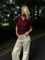 Modelfoto af pige i en bordeaux Hadley polo og cremefarvede Adrianna jeans. Alt er fra BySofieSønderby