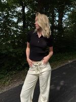 Modelfoto af pige i en sort Hadley polo og cremefarvede Adrianna jeans. Alt er fra BySofieSønderby