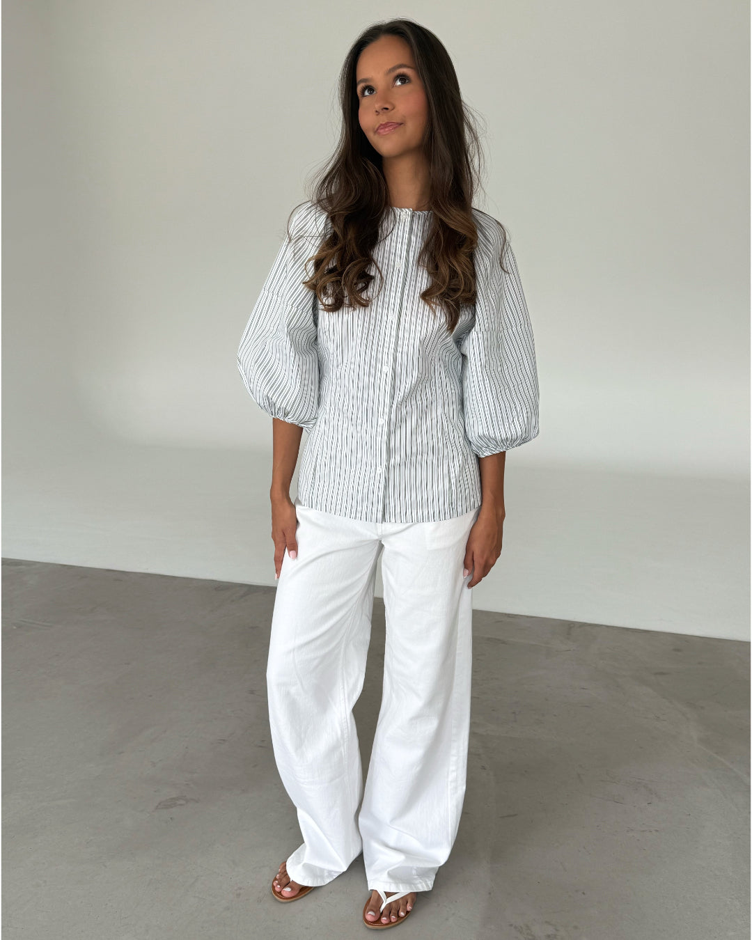 Modelfoto af pige som bærer grøn-hvid stribet HELEN skjorte og hvide jeans. Alt er fra BySofieSønderby