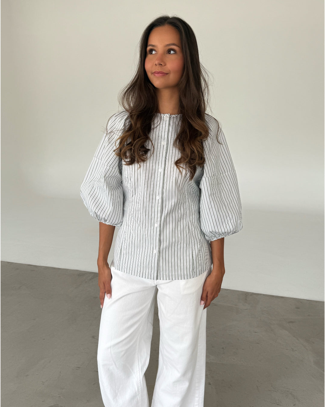 Modelfoto af pige som bærer grøn-hvid stribet HELEN skjorte og hvide jeans. Alt er fra BySofieSønderby