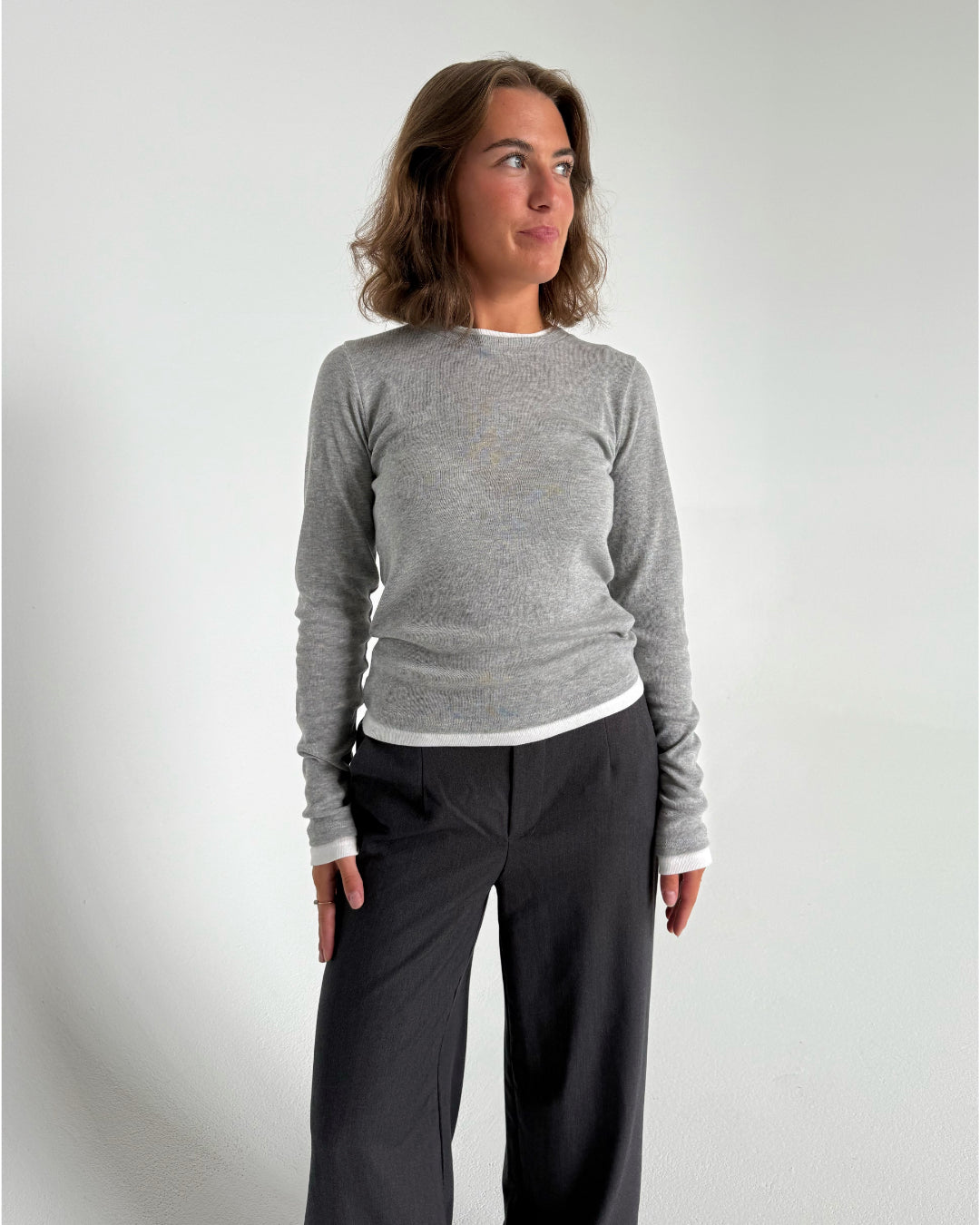Modelfoto af pige som bærer en langærmet Henna bluse i grå, samt mørkegrå Lisa bukser. Alt fra By Sofie Sønderby