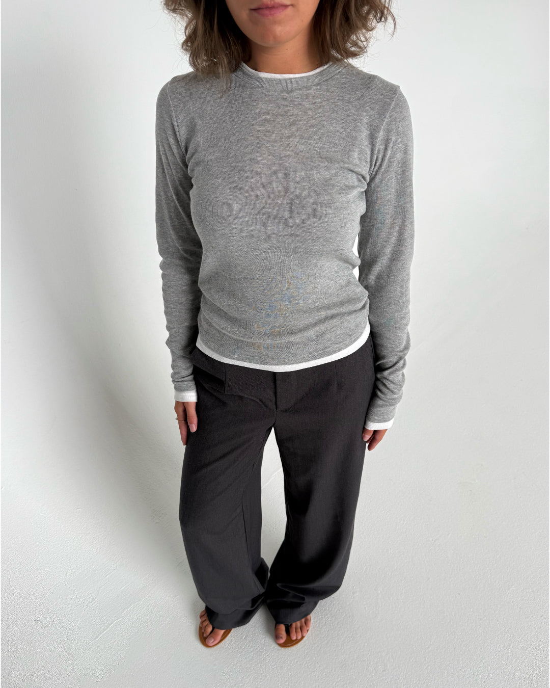 Modelfoto af pige som bærer en langærmet Henna bluse i grå, samt mørkegrå Lisa bukser. Alt fra By Sofie Sønderby