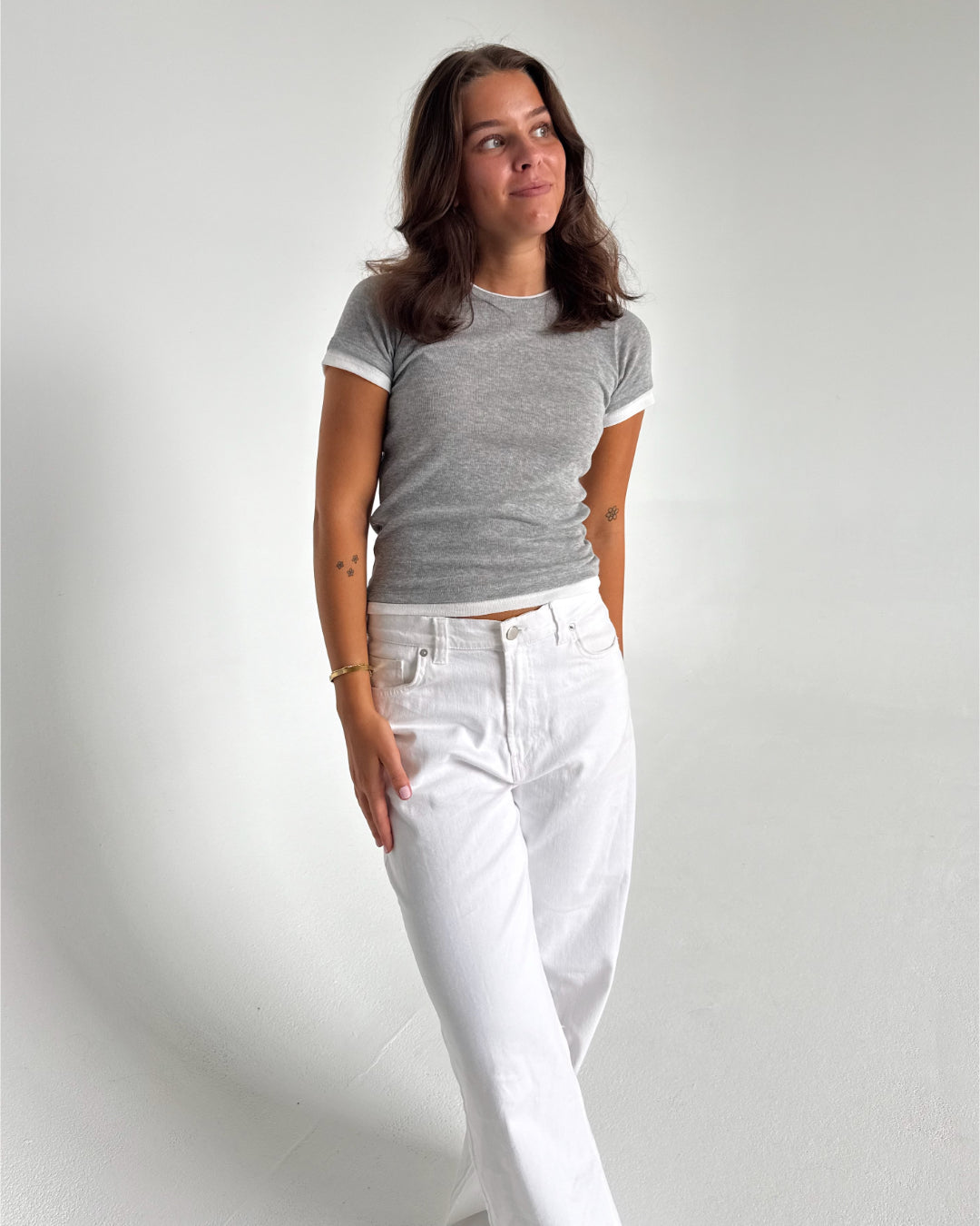Modelfoto af pige som bærer en Henna t-shirt i grå, samt hvide Nanna jeans. Alt fra By Sofie Sønderby
