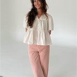 Modelfoto af pige som bærer creme-farvet HOPE top med v-hals og lyserøde jeans. Alt er fra BySofieSønderby