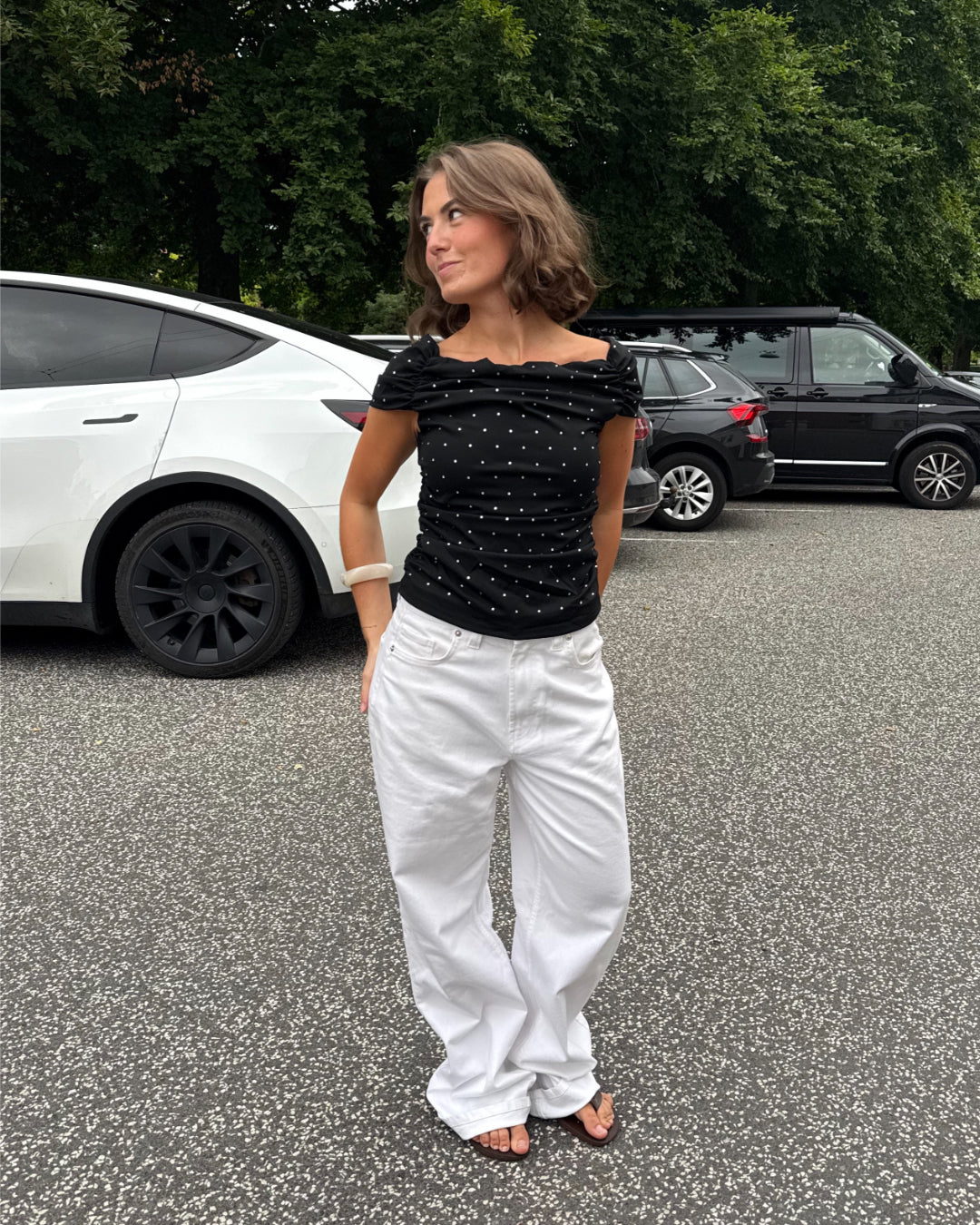 Modelfoto af pige med REYA top, sort og NANNA jeans, hvid - begge fra BySofieSønderby
