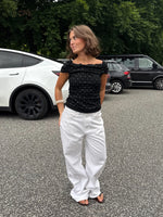 Modelfoto af pige med REYA top, sort og NANNA jeans, hvid - begge fra BySofieSønderby