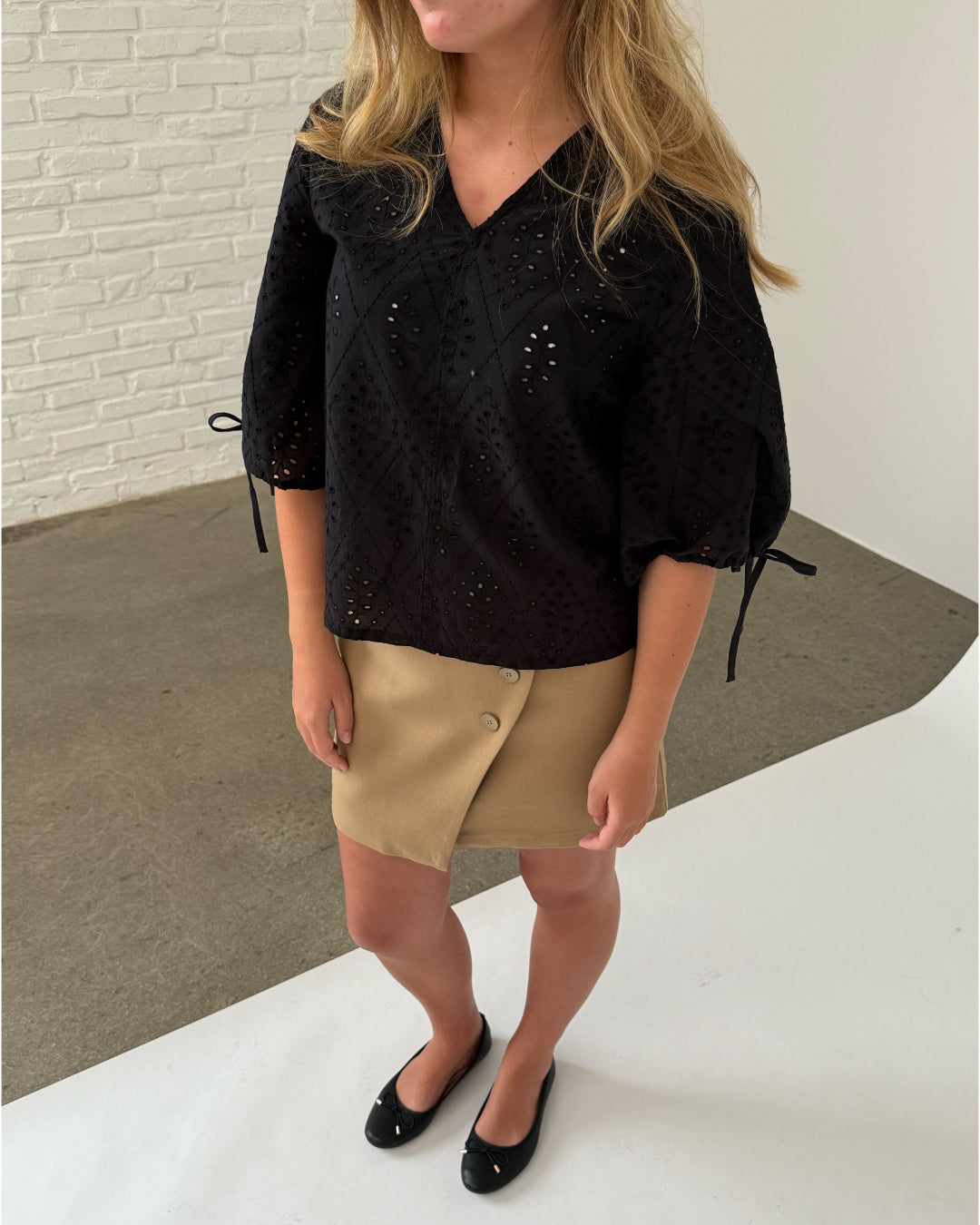 Modelfoto af pige iklædt JOELLA bluse, sort og NOAH nederdel, sand - begge fra BySofieSønderby