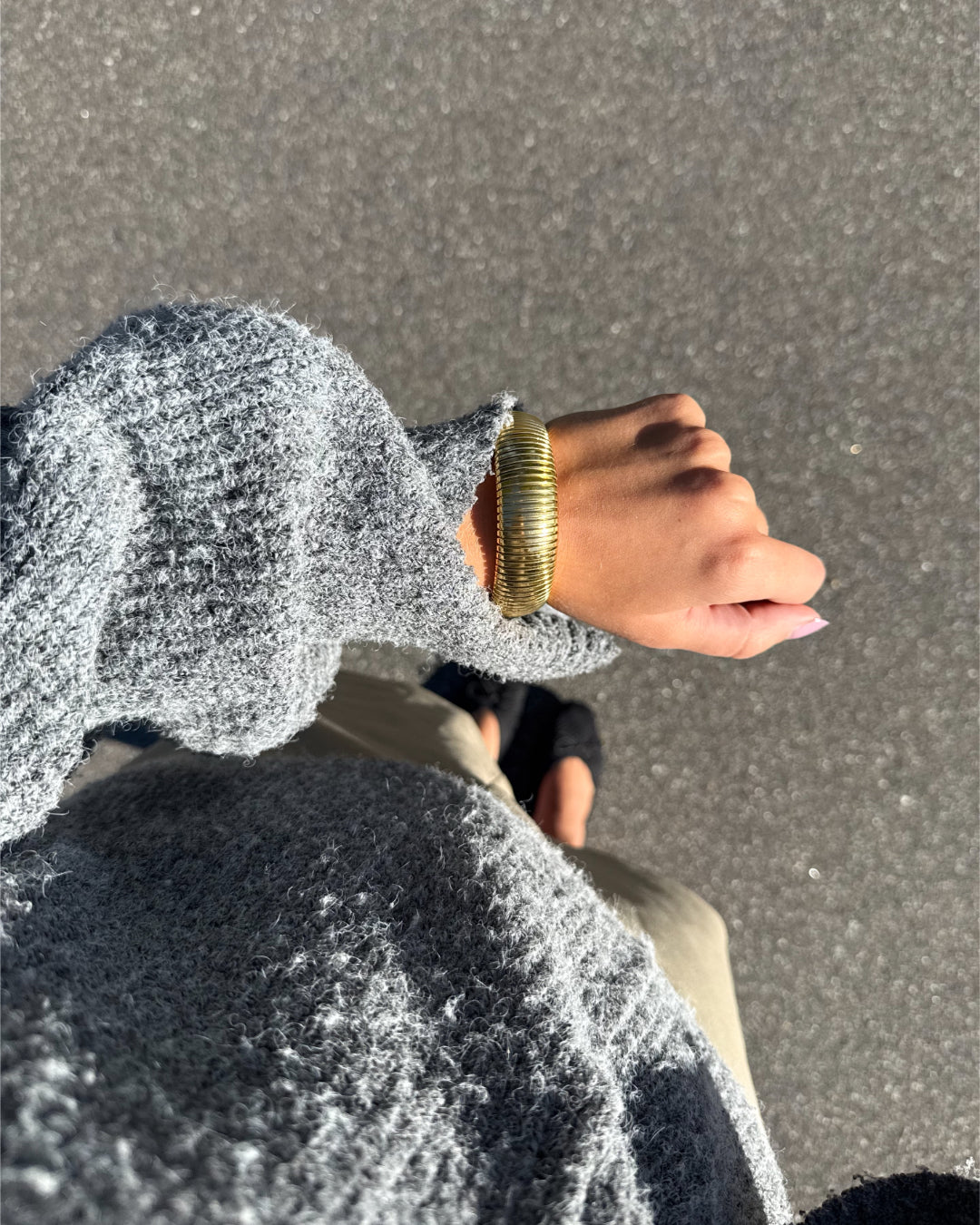 Modelfoto af en Lenora guld armbånd. Baggrund er grå. Fra BySofieSønderby
