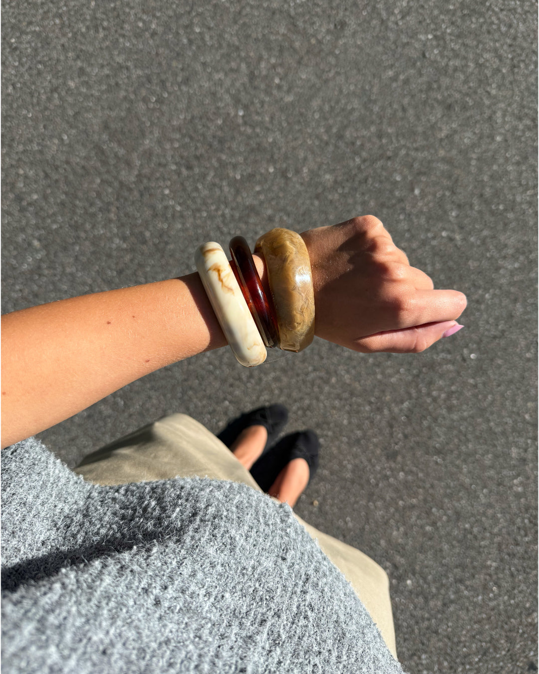 Modelfoto af Leona armbånd sæt bestående af 3 armbånd i brunlige nuancer. Baggrund er grå. Fra BySofieSønderby