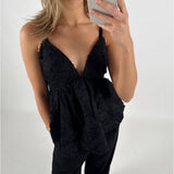 En person iført en sort top med stropper tager et spejlfoto. Personen har lyst hår og står i et lyst rum.