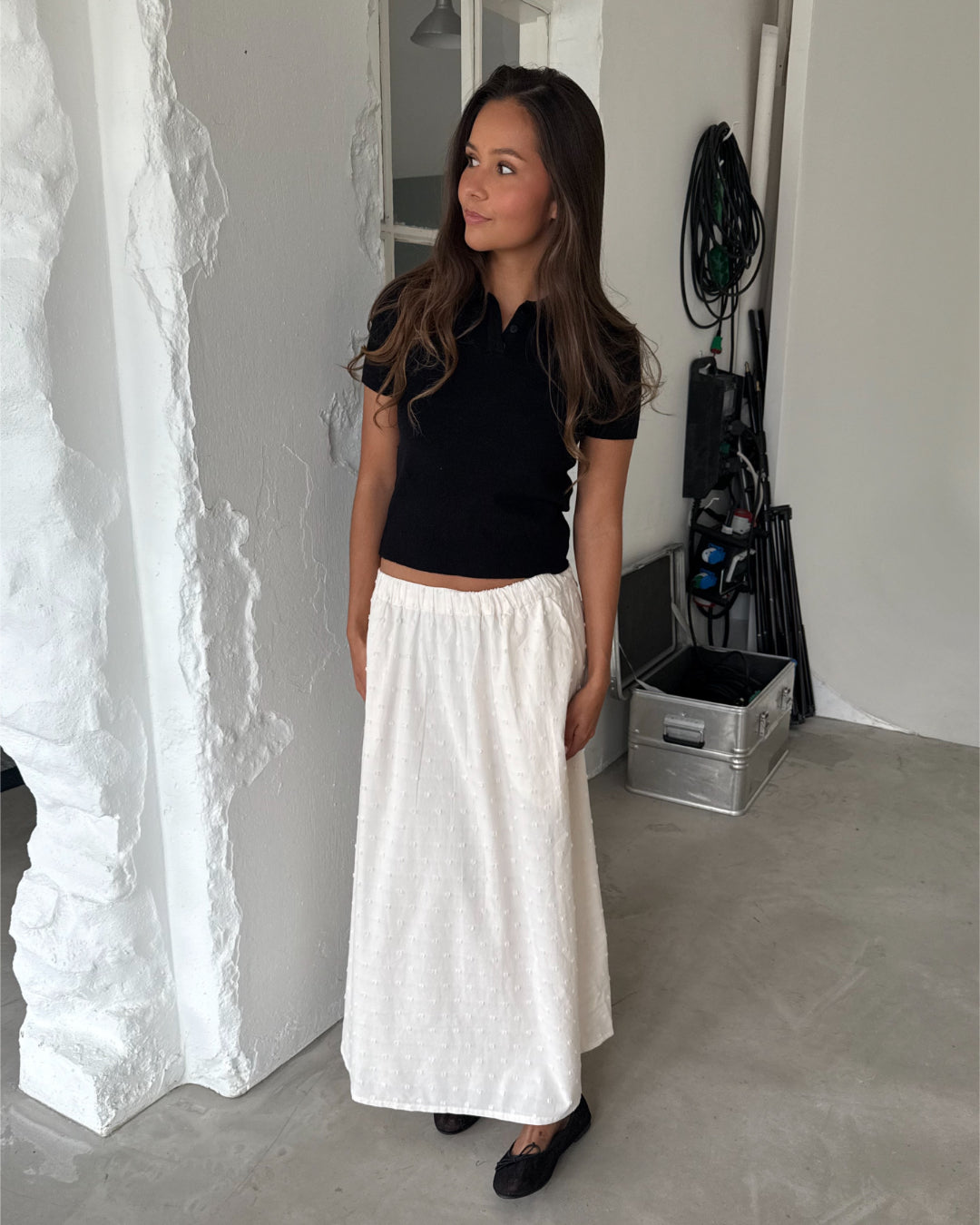 Modelfoto af pige med LILOU polo, sort og SUNELA nederdel, hvid - begge fra BySofieSønderby