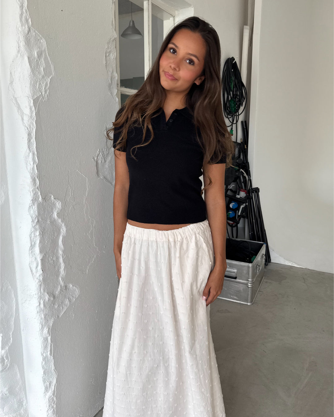 Modelfoto af pige med LILOU polo, sort og SUNELA nederdel, hvid - begge fra BySofieSønderby