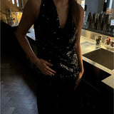 En person iført en sort, glitrende top står ved en bar med metaloverflader og cocktailshakere i baggrunden. Skiltet "Negroni" ses svagt på væggen.