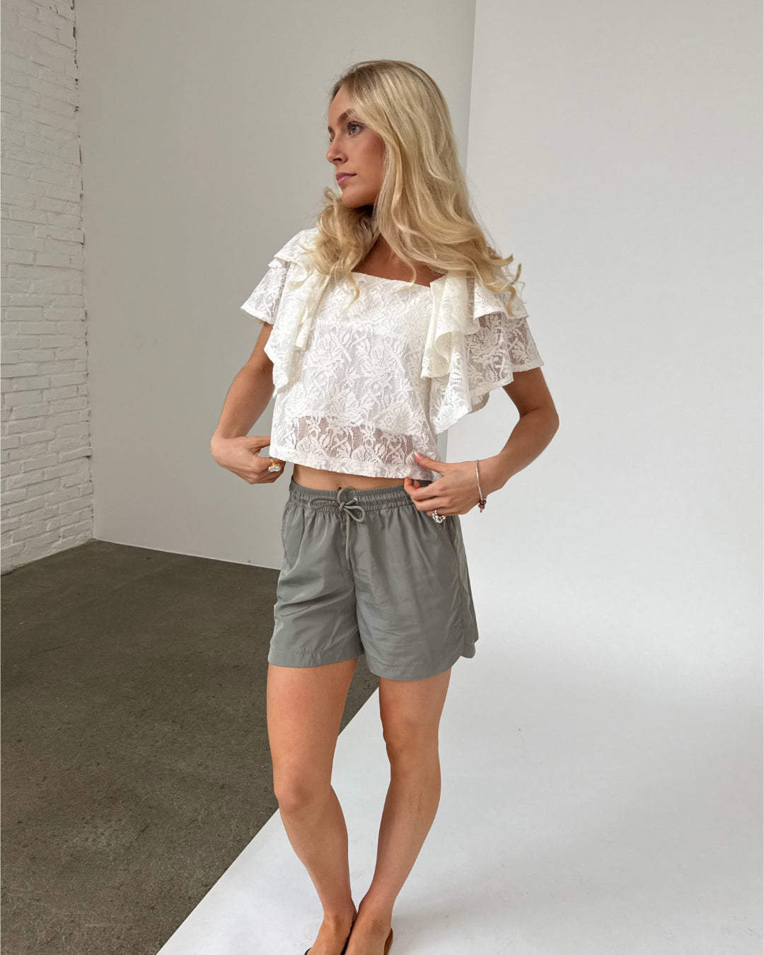Modelfoto af pige iklædt LUCILLE blonde bluse, hvid og LANA shorts, grøn - begge fra BySofieSønderby