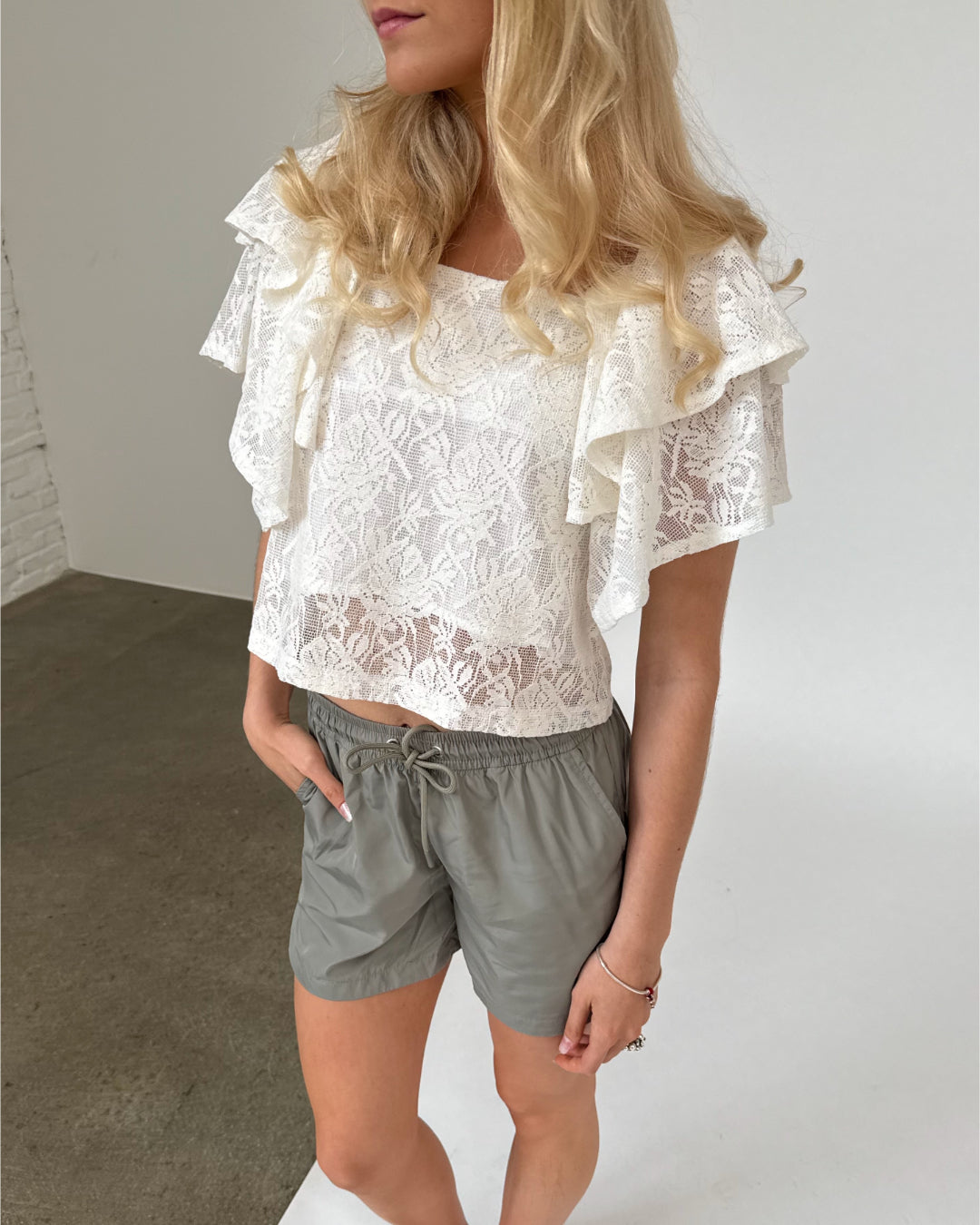 Modelfoto af pige iklædt LUCILLE blonde bluse, hvid og LANA shorts, grøn - begge fra BySofieSønderby