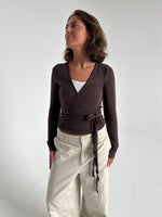 Modelfoto af pige i brun Luna wrapbluse og beige bukser. Fra BySofieSønderby