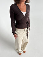 Modelfoto af pige i brun Luna wrapbluse og beige bukser. Fra BySofieSønderby