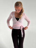 Modelfoto af pige i lyserød Luna wrap bluse og brune Sania bukser. Fra BySofieSønderby