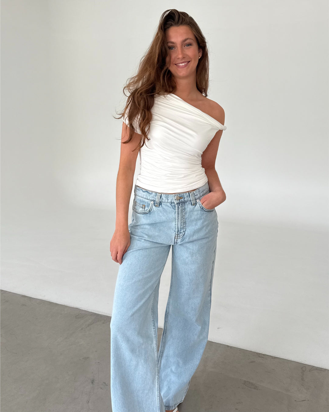 Modelfoto af pige med MILENA off shoulder top, hvid og NANNA jeans, lyseblå - begge fra BySofieSønderby