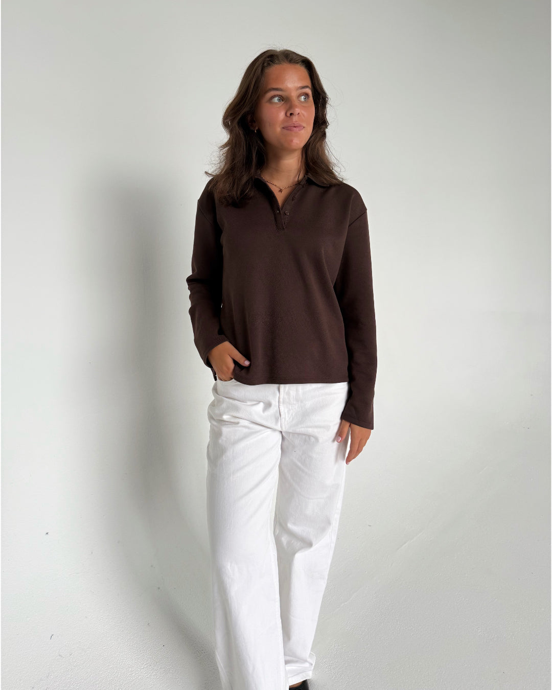 Modelfoto af pige der bærer en brun Millie bluse, samt hvide Nanna jeans. Alt fra BySofieSønderby
