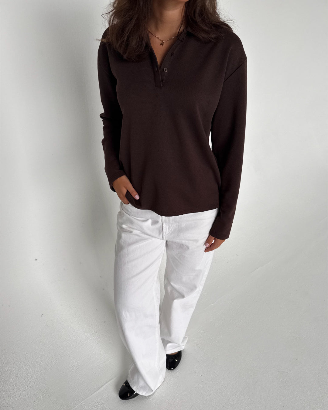 Modelfoto af pige der bærer en brun Millie bluse, samt hvide Nanna jeans. Alt fra BySofieSønderby
