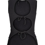 En sort, ærmeløs top med tre runde udskæringer foran, hver bundet med en snor. Stoffet har en let tekstur, formgivet til afslappet brug.