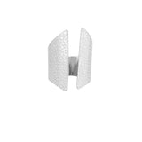 Sølvring med et åbent design og præget tekstur, der skaber et moderne og elegant udseende. Baggrunden er enkel og hvid, fremhæver ringens detaljer.