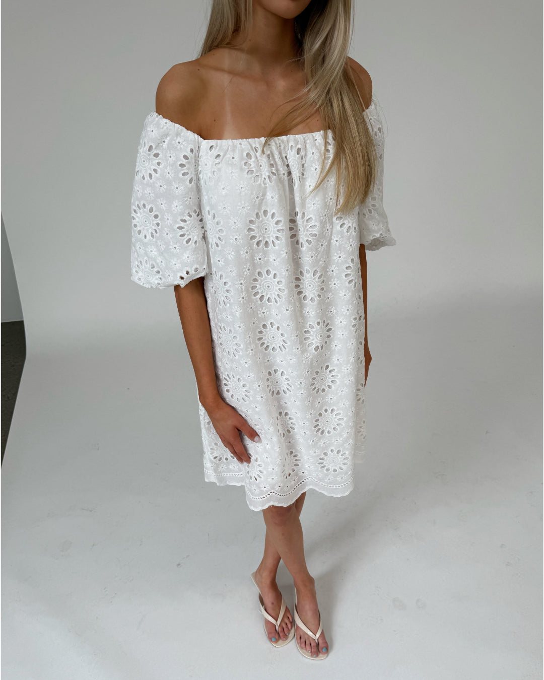 Modelfoto af pige som bærer hvid PALMA off-shoulder kjole med mønster. Alt er fra BySofieSønderby
