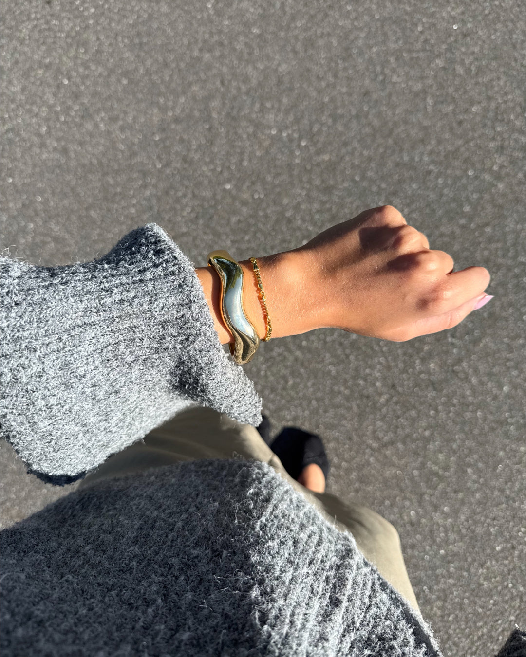 Modelfoto af en Robin guld armbånd. Baggrund er grå. Fra BySofieSønderby