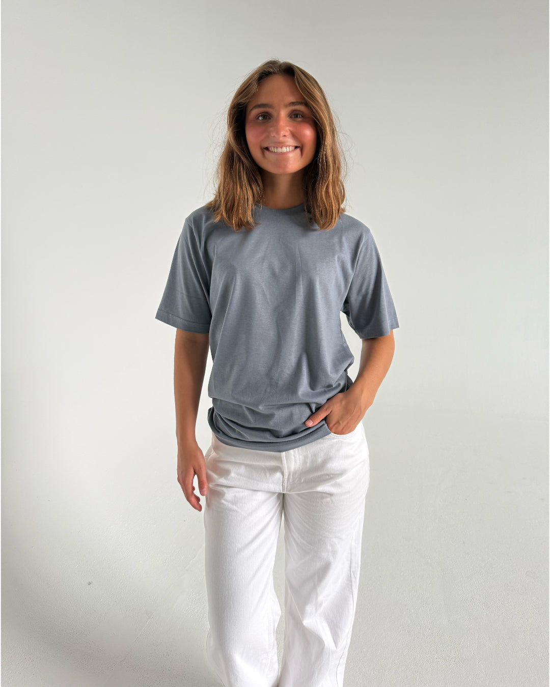 Modelfoto af pige som bærer en SNDRB tee i farven stone, samt et par hvide jeans. Alt fra By Sofie Sønderby