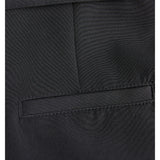 Lomme af sort stof, syet ind i et par bukser, med en skrå åbning. Stoffet er jævnt vævet, og sømmene er præcise, hvilket giver et elegant udseende.