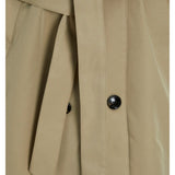 Beige trench coat med bælte, der hænger løst foran. To sorte knapper fastgør stoffet på hver side. Baggrunden er neutral, hvilket fremhæver tøjet.