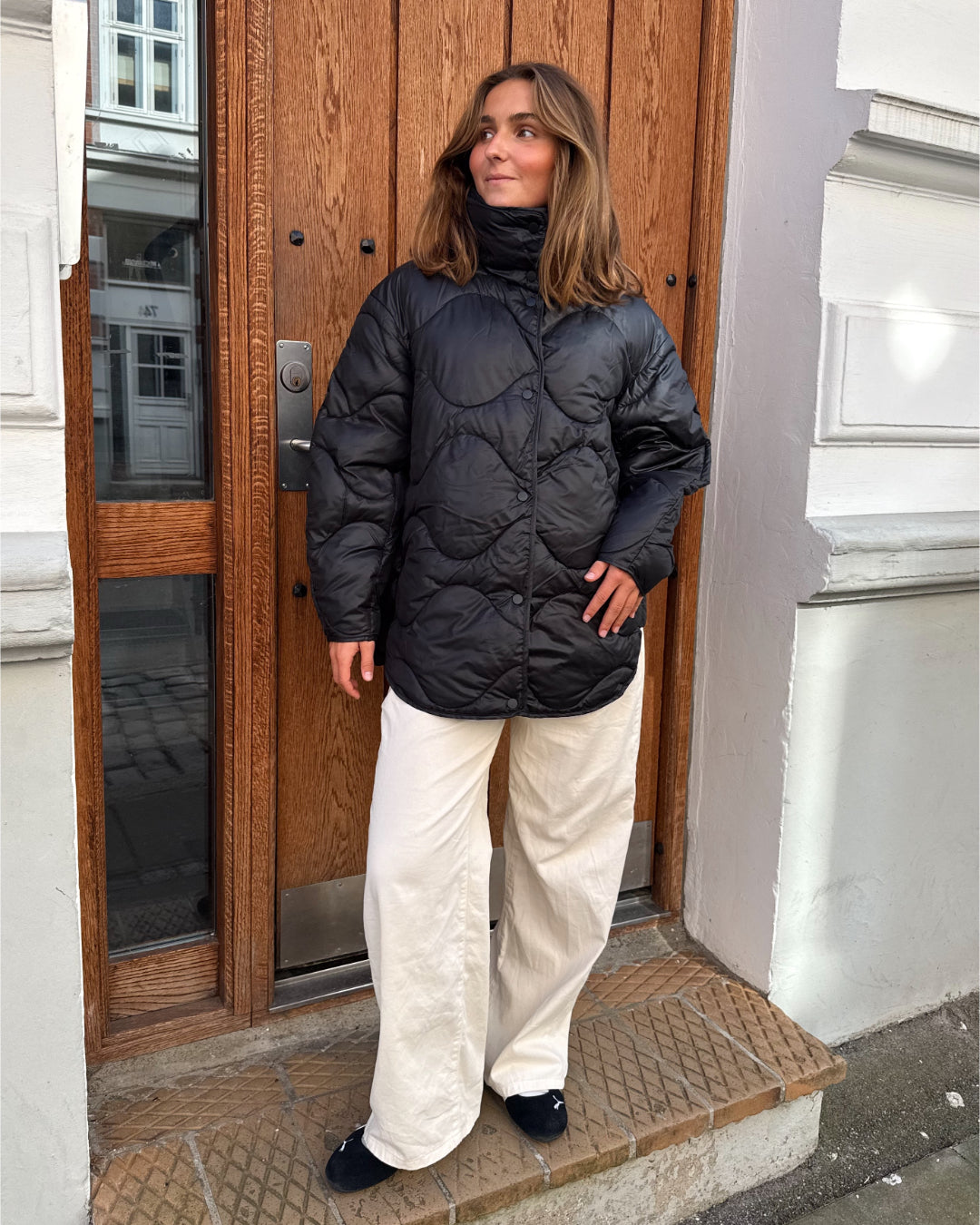 Modelfoto af pige i sort Stella jakke og beigefarvede Arianna jeans. Alt er fra BySofieSønderby