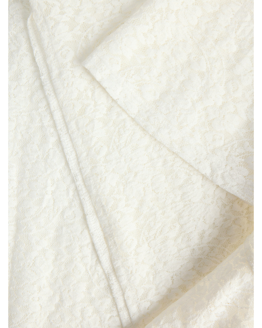 Hvidt blondeagtigt materiale ligger i overlappende lag med et delikat mønster, der skaber et sofistikeret og elegant udseende i en neutral baggrund uden synlig tekst.