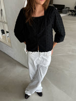 Modelfoto af pige med SUNELA bluse, sort og NANNA jeans, hvid - begge fra BySofieSønderby